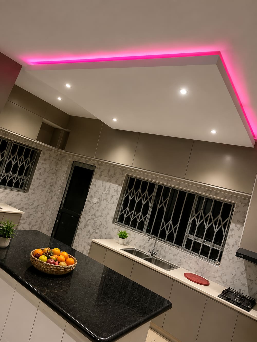 Modern kitchen with a bulkhead ceiling, concealed pink LED strip lighting and recessed downlights